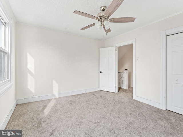 unfurnished bedroom featuring light carpet, ceiling fan, ornamental molding, a textured ceiling, and a closet