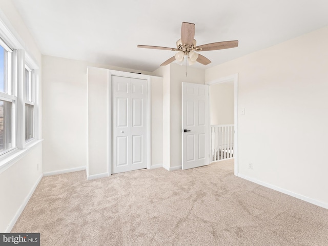 unfurnished bedroom with ceiling fan, light colored carpet, and a closet