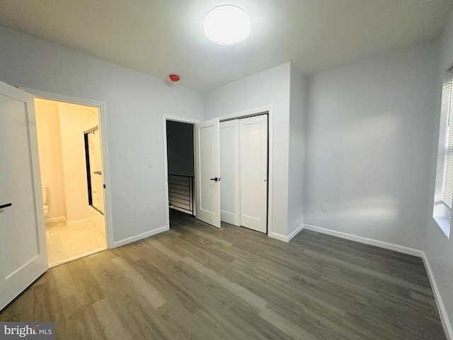 unfurnished bedroom with connected bathroom, a closet, and hardwood / wood-style flooring