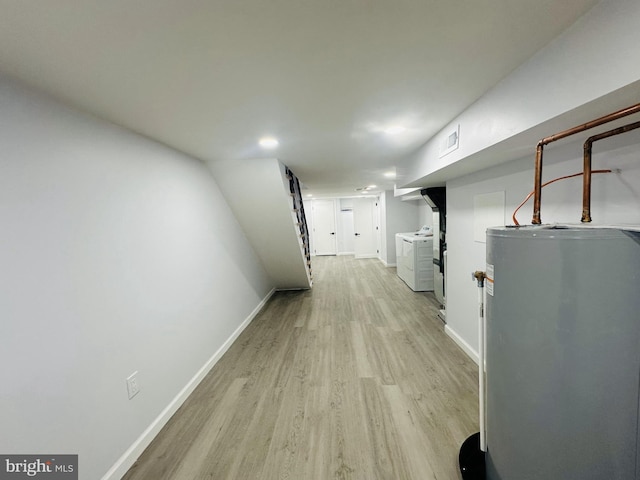 corridor with washing machine and clothes dryer, light wood-type flooring, and gas water heater