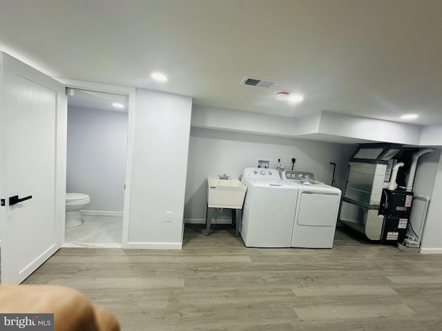 laundry area with washing machine and clothes dryer and light wood-type flooring