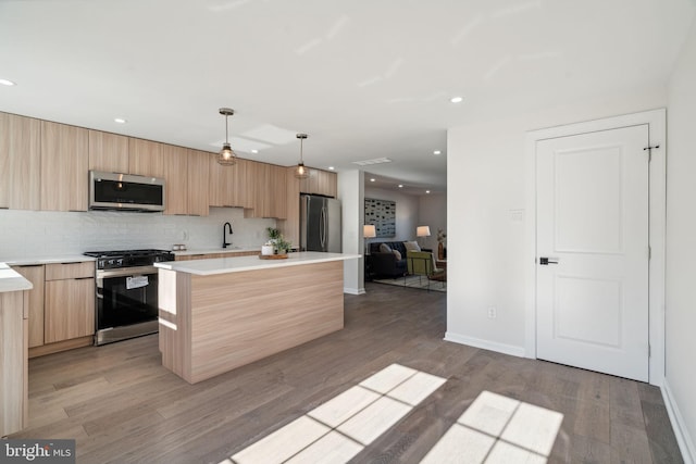 kitchen with a kitchen island, wood-type flooring, decorative light fixtures, and appliances with stainless steel finishes