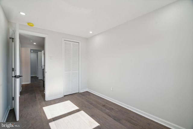 unfurnished bedroom featuring dark wood-type flooring and a closet