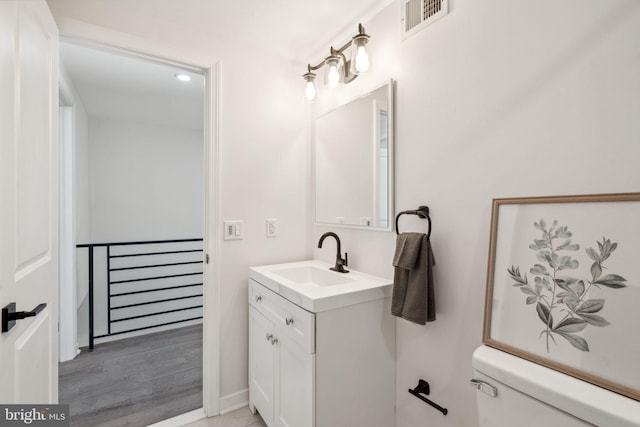 bathroom with hardwood / wood-style floors, vanity, and toilet