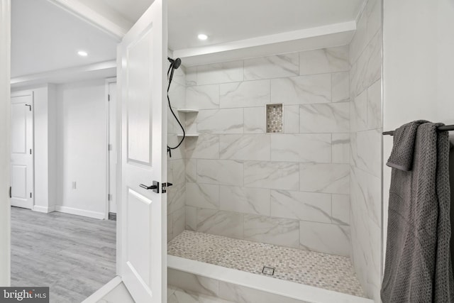 bathroom with a tile shower and wood-type flooring