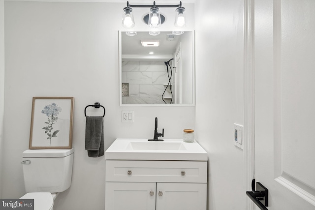 bathroom featuring tiled shower, vanity, and toilet