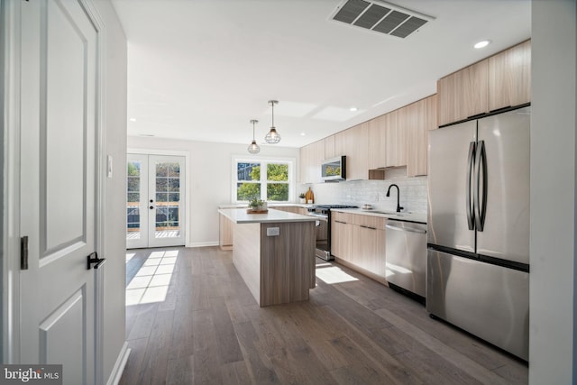 kitchen featuring sink, decorative light fixtures, a kitchen island, dark hardwood / wood-style flooring, and stainless steel appliances