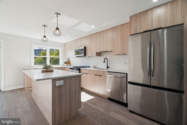 kitchen with sink, hardwood / wood-style floors, a center island, and appliances with stainless steel finishes