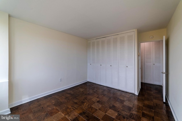 unfurnished bedroom with dark parquet flooring and a closet