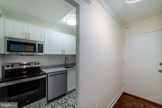 kitchen with sink, white cabinetry, ornamental molding, appliances with stainless steel finishes, and dark parquet floors