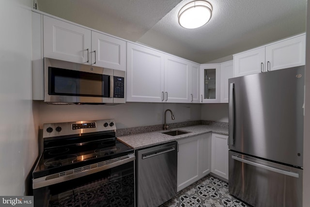 kitchen featuring light stone counters, stainless steel appliances, white cabinetry, and sink