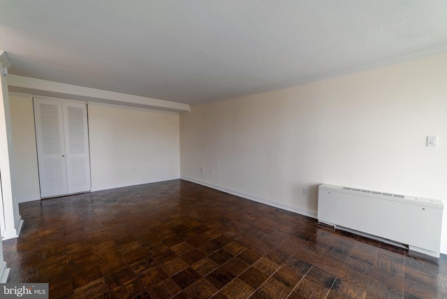 unfurnished room with radiator heating unit and a textured ceiling