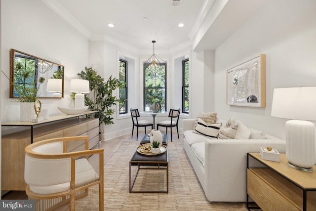 living room with light hardwood / wood-style floors, ornamental molding, a wealth of natural light, and a chandelier