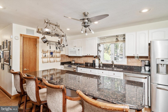 kitchen featuring white cabinetry, sink, a kitchen bar, a kitchen island, and appliances with stainless steel finishes