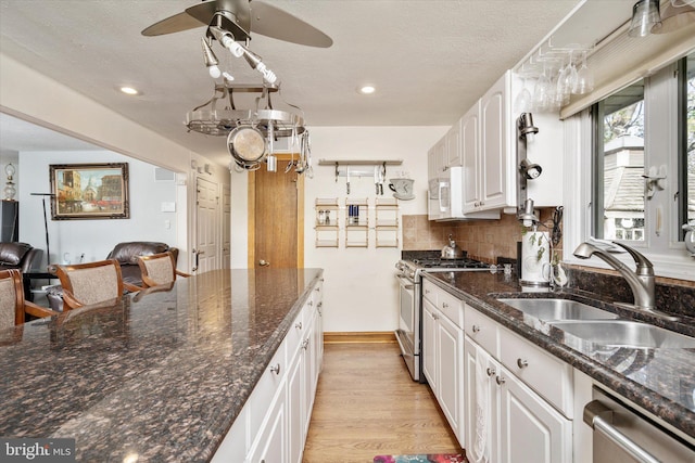 kitchen featuring sink, light hardwood / wood-style floors, decorative backsplash, white cabinets, and appliances with stainless steel finishes