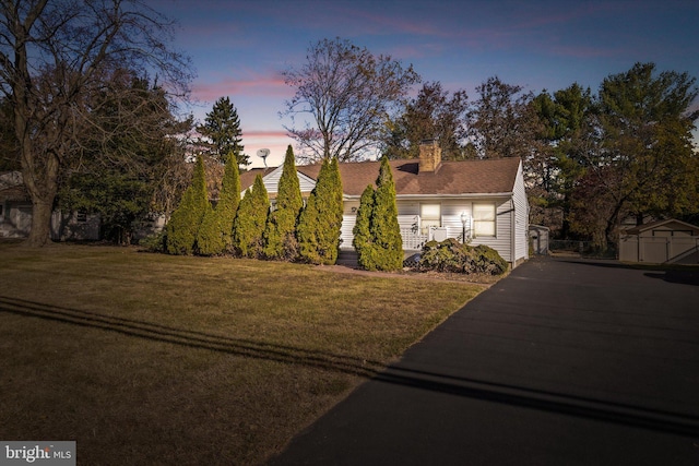 cape cod-style house with a yard and a shed