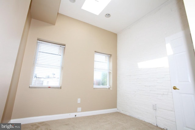 spare room with light colored carpet and lofted ceiling with skylight