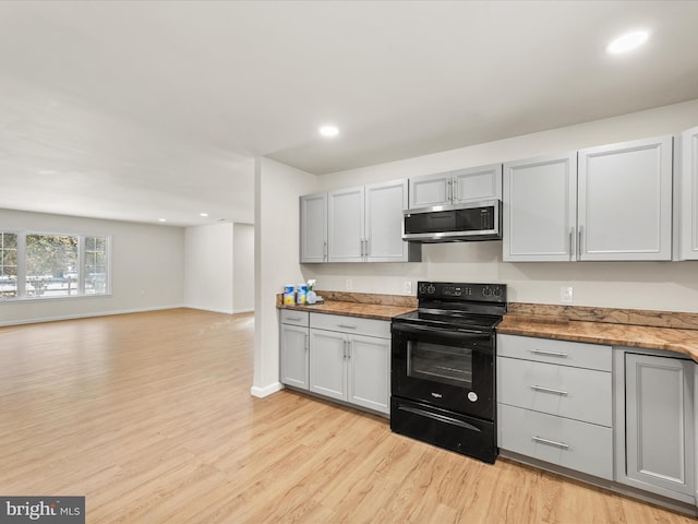 kitchen with light wood-type flooring and black / electric stove