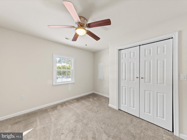 unfurnished bedroom with ceiling fan, light carpet, and a closet