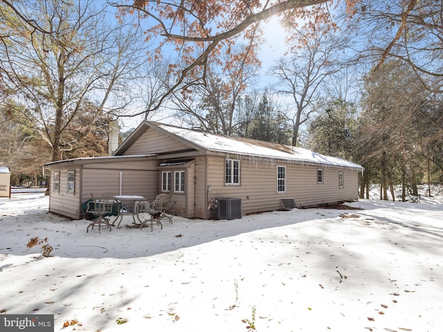 snow covered back of property featuring cooling unit