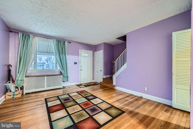 entrance foyer featuring hardwood / wood-style flooring, a textured ceiling, and radiator