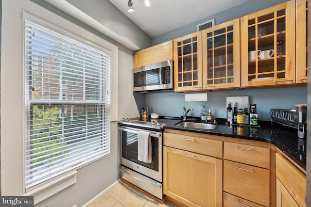 kitchen with a wealth of natural light, sink, light tile patterned floors, and stainless steel appliances