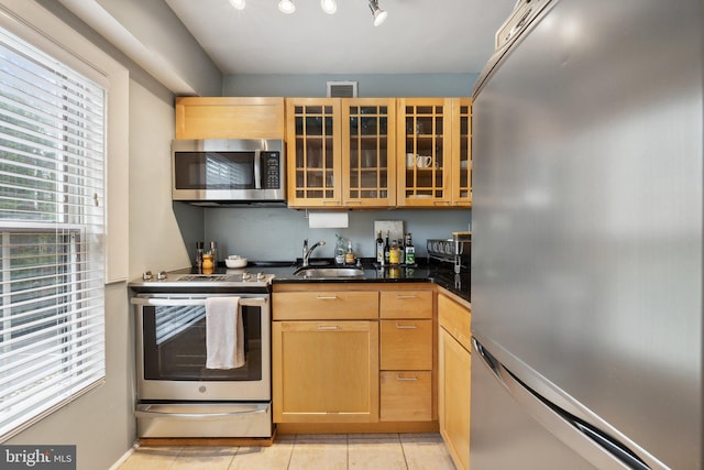 kitchen with light brown cabinetry, light tile patterned floors, sink, and appliances with stainless steel finishes