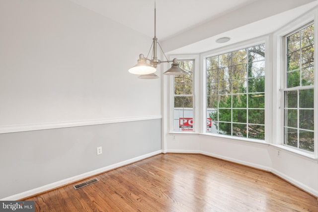 unfurnished dining area with a notable chandelier and wood-type flooring