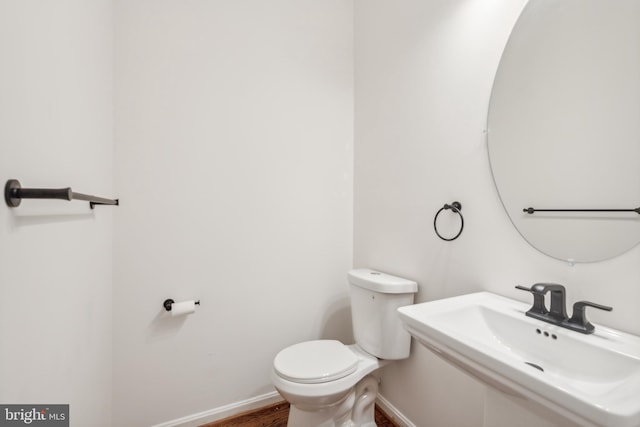 bathroom featuring wood-type flooring, toilet, and sink