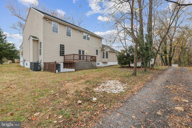 rear view of house featuring central air condition unit, a lawn, and a deck