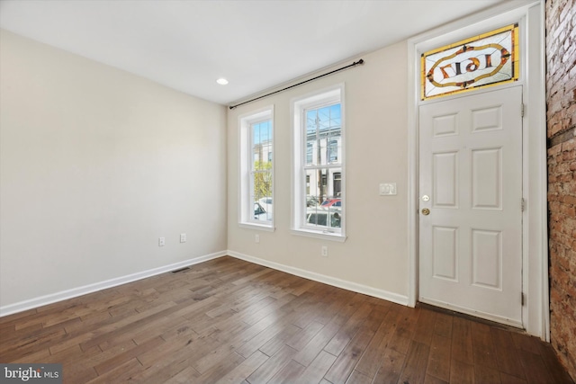 entryway with brick wall and dark hardwood / wood-style floors