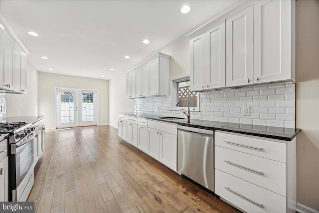 kitchen with sink, french doors, light hardwood / wood-style flooring, white cabinets, and appliances with stainless steel finishes