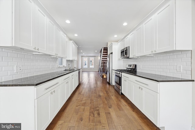 kitchen with white cabinetry, sink, stainless steel appliances, and light hardwood / wood-style floors