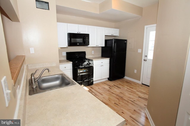 kitchen featuring sink, light hardwood / wood-style floors, white cabinetry, and black appliances