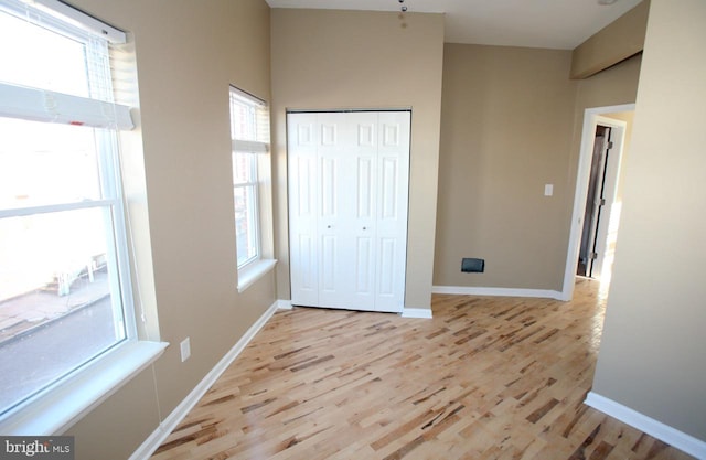 unfurnished bedroom featuring a closet, light hardwood / wood-style floors, and multiple windows