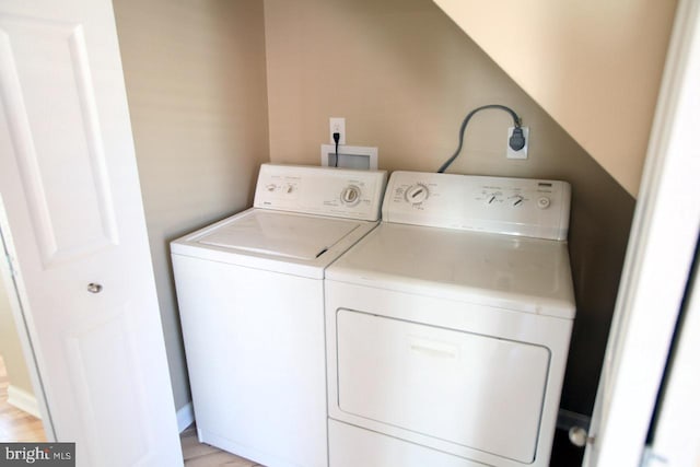 laundry area with washing machine and clothes dryer and light hardwood / wood-style floors