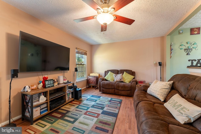 living room featuring hardwood / wood-style flooring, ceiling fan, and a textured ceiling