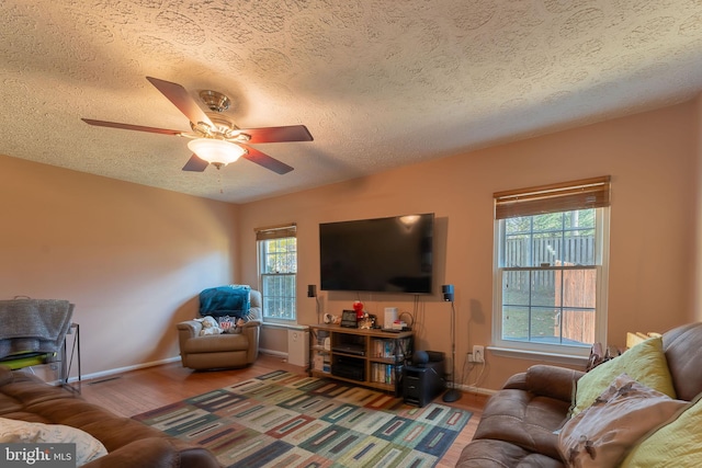 living room with wood-type flooring, a textured ceiling, ceiling fan, and a healthy amount of sunlight