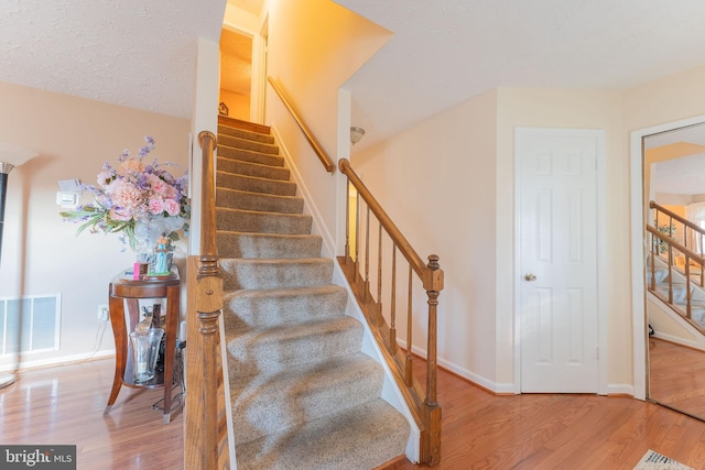 stairway featuring hardwood / wood-style floors and a textured ceiling