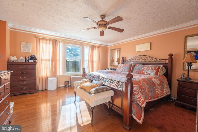 bedroom featuring hardwood / wood-style floors, ceiling fan, ornamental molding, and a textured ceiling