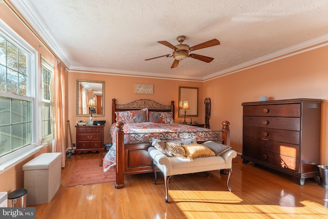 bedroom featuring ceiling fan, light hardwood / wood-style flooring, a textured ceiling, and ornamental molding