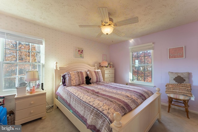 bedroom with ceiling fan, light carpet, and a textured ceiling