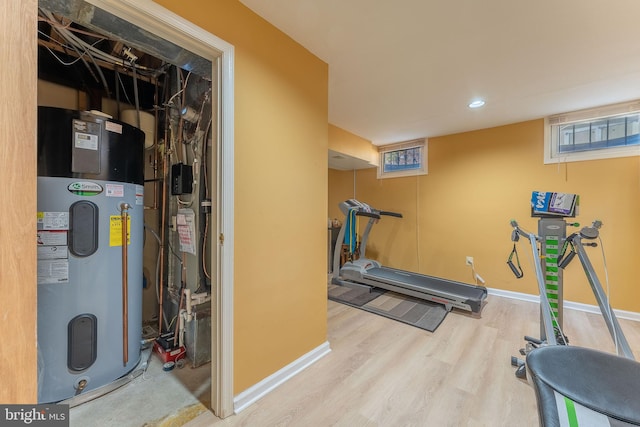 workout room with hybrid water heater and light wood-type flooring