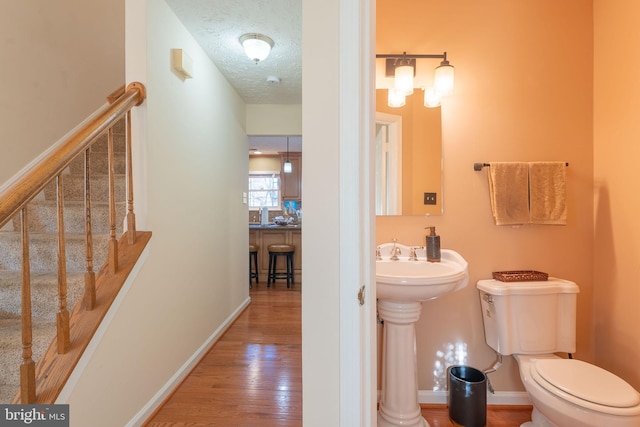 bathroom with hardwood / wood-style floors, toilet, and a textured ceiling