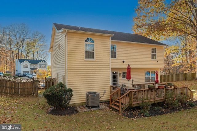 back of property with central air condition unit, a lawn, and a deck