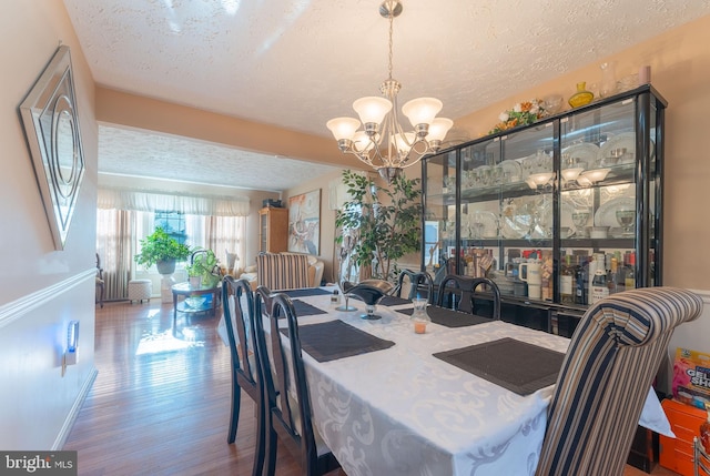 dining room featuring hardwood / wood-style flooring, a textured ceiling, and an inviting chandelier