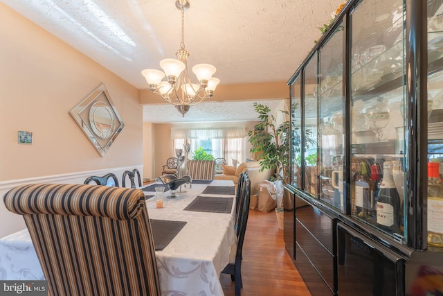 dining area featuring dark hardwood / wood-style flooring, a chandelier, and a textured ceiling