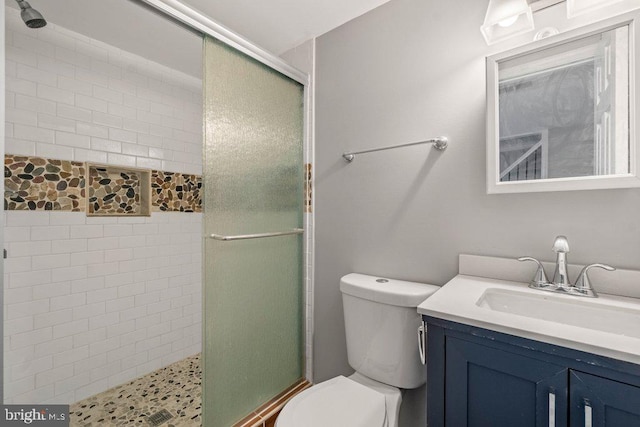 bathroom with vanity, toilet, and a shower with door