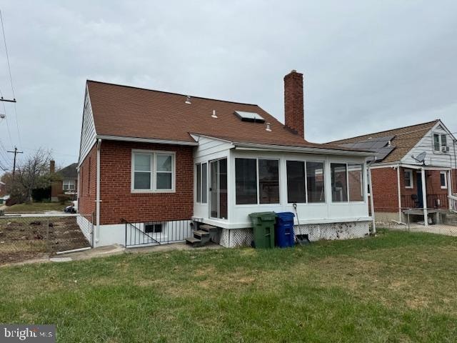 rear view of property featuring a yard and a sunroom