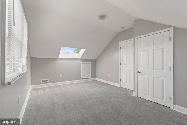 additional living space with vaulted ceiling with skylight and carpet flooring